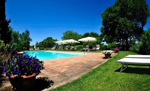 a swimming pool with tables and umbrellas in a yard at Borgo Fastelli in Sarteano