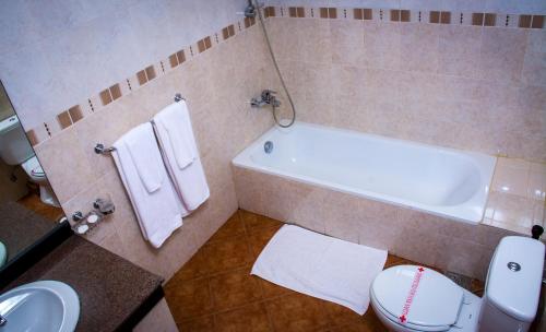 a bathroom with a tub and a toilet and a sink at Hotel Lakefield in Kandy