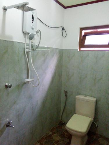 a bathroom with a shower and a toilet in it at Deshan Homestay & Restaurant in Tangalle