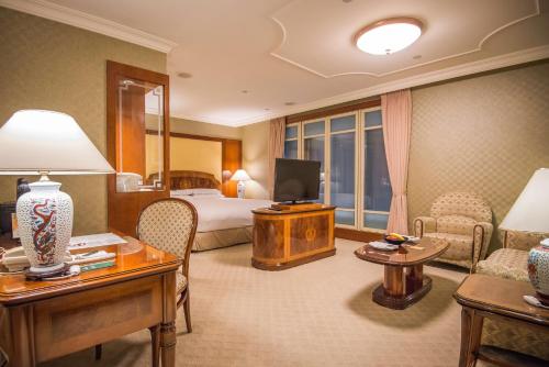 una camera d'albergo con letto e TV di Evergreen Laurel Hotel Taipei a Taipei