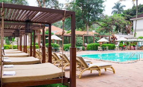 a row of chaise lounge chairs next to a swimming pool at Fairway Boutique Hotel - Kampala, Uganda in Kampala