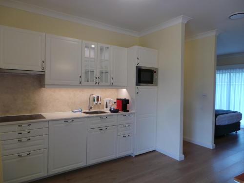 a kitchen with white cabinets and white appliances at Colin's Garden in Bomaderry