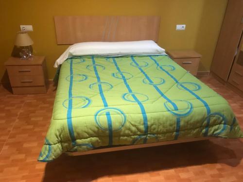 a bed with a green comforter in a bedroom at Apartamentos Duquesa Sierra Nevada in Pinos Genil