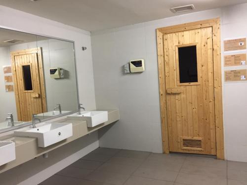 a bathroom with two sinks and a wooden door at Southville Stay 2 @ Savanna Executive Suite in Kampong Tangkas
