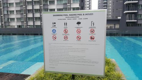 a sign next to a swimming pool next to a building at Southville Stay 2 @ Savanna Executive Suite in Kampong Tangkas