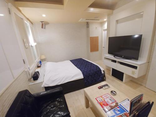 a hotel room with a bed and a flat screen tv at Hotel Allure (Adult Only) in Nagoya