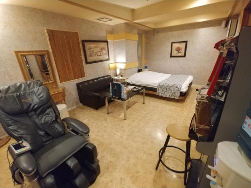 a hotel room with a bed and a room with a chair at Hotel Allure (Adult Only) in Nagoya