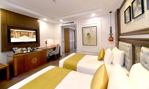 a hotel room with two beds and a desk at Garco Dragon Hotel 2 in Hanoi