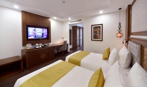 a hotel room with two beds and a television at Garco Dragon Hotel 2 in Hanoi