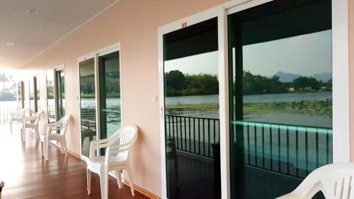 a balcony with white chairs and a view of the water at Tamarind Guesthouse in Kanchanaburi