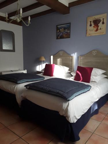 2 letti in una camera con pareti blu e cuscini rossi di Mas de l'ile ad Avignone