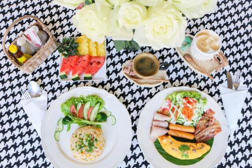 a table with plates of food and a basket of flowers at My Way Hua Hin Music Hotel SHA Extra Plus in Hua Hin