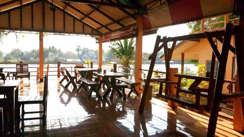 un restaurante con mesas de madera y sillas en un patio en Tamarind Guesthouse en Kanchanaburi