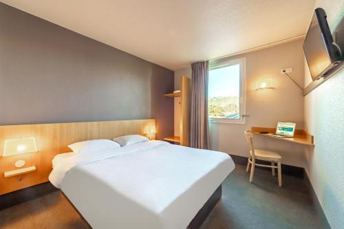 um quarto de hotel com uma grande cama branca e uma janela em B&B HOTEL Toulon Ollioules em Ollioules