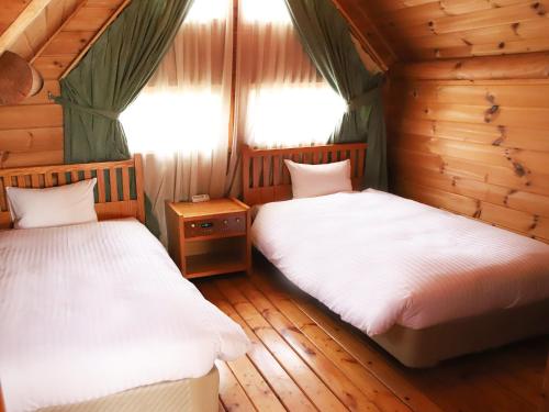 two beds in a room with wooden floors and windows at The Day Osaka in Osaka