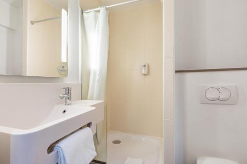 a white bathroom with a sink and a shower at B&B HOTEL Lille Centre Grand Palais in Lille