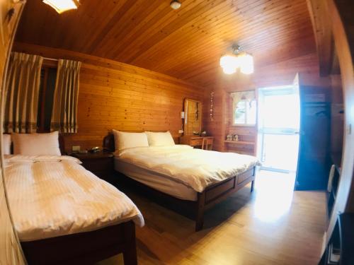 a bedroom with two beds and a wooden wall at He Feng Homestay in Hualing