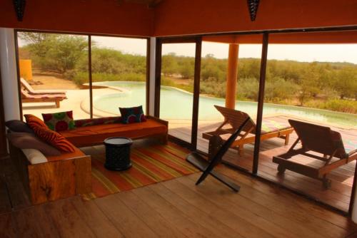 a screened in porch with chairs and a swimming pool at Le Lodge Dalaal Diam in Somone