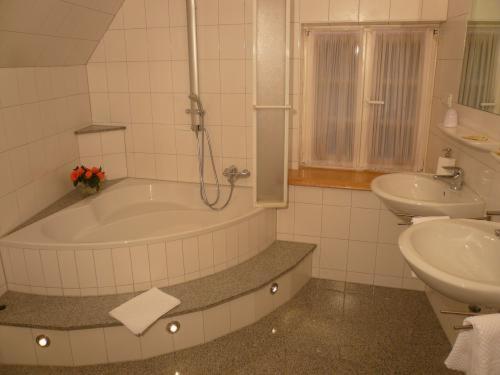 a bathroom with a bath tub and a sink at Elektro-Hotel Rosenhaus GmbH in Velbert