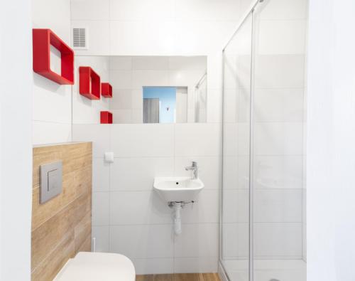 a white bathroom with a toilet and a sink at Pensjonat Maja in Nowy Sącz