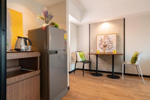 a kitchen with a refrigerator and a table with chairs at The Home Hotel SHA in Bangkok