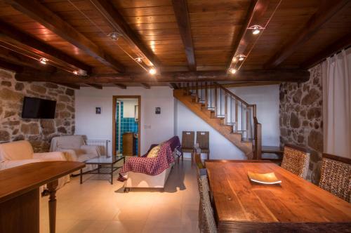 a living room with a wooden table and a staircase at O Canto da Terra in Pantón