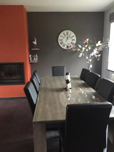a dining room table with chairs and a clock on the wall at Ferme de la Petite Fagne in Spa