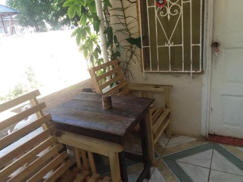 einen Holztisch und zwei Stühle auf einer Veranda in der Unterkunft T&T - Tatty and Tony Guesthouse in Negril