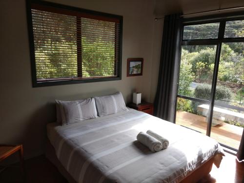a bedroom with a large white bed with a window at Piha Beachstay Accommodation in Piha