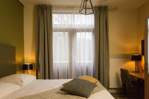 een slaapkamer met een bed en een raam met gordijnen bij Bed & Breakfast Van Marion in Oostvoorne