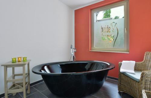 a black bath tub in a room with a chair at Landhotel Schnuck in Schneverdingen