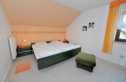 a bedroom with a bed and a green chair at Ferienwohnung Brunner - Haus am See in Nagel