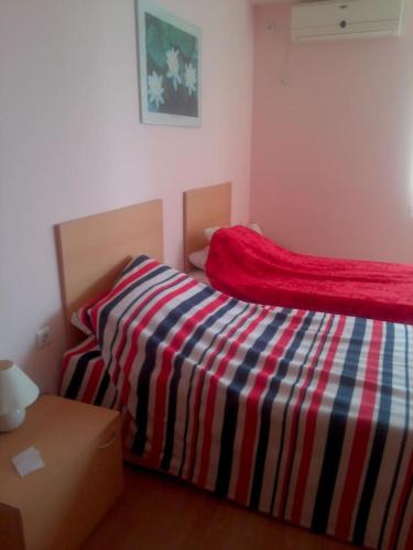 a bedroom with a bed with a colorful striped blanket at Magical apartment in Marina view Fort beach in Sveti Vlas