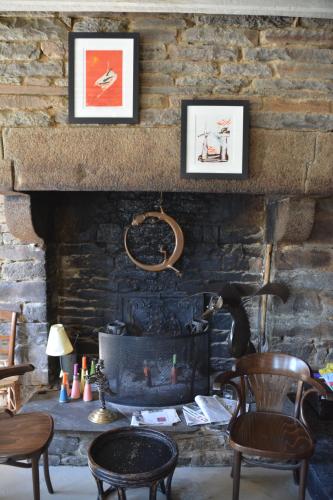 a living room with a stone fireplace with two chairs at Le Relais in Saint-Sauveur-la-Pommeraye
