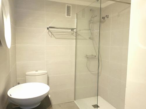 een badkamer met een toilet en een glazen douche bij By The Beach in Málaga