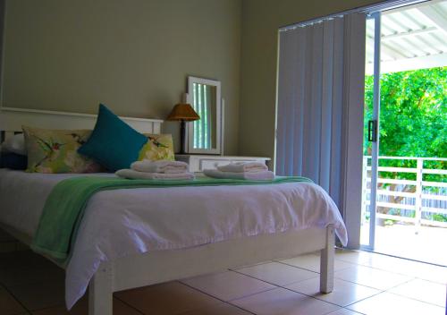 1 dormitorio con 1 cama y puerta corredera de cristal en Aloe Ridge en Mossel Bay