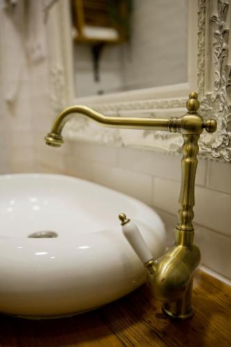 a bathroom with a white sink with a gold piping at NINHO SALOIO in Venda do Pinheiro