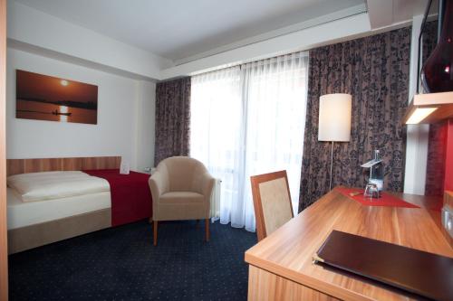 a hotel room with a bed and a desk at Hotel Knaus am Hafen in Uhldingen-Mühlhofen