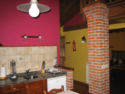 a kitchen with a red wall and a brick pillar at La Portiella in Bueres