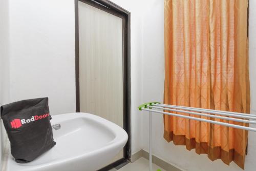 a bathroom with a black bag sitting on top of a sink at RedDoorz Syariah near RSU Suaka Insan Banjarmasin in Banjarmasin