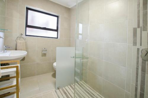 a bathroom with a shower and a toilet and a sink at Herolds Bay Accommodation - Hiers Ons Weer Downstairs in Herolds Bay
