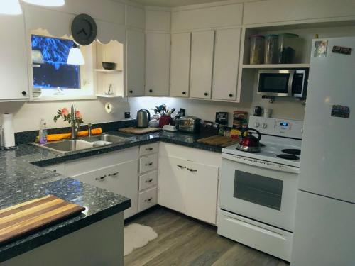 uma cozinha com armários brancos e um frigorífico branco em Billie's Backpackers Hostel em Fairbanks