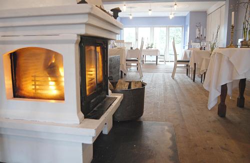 a fireplace in the middle of a dining room with tables at Nørre Vissing Kro in Nørre Vissing