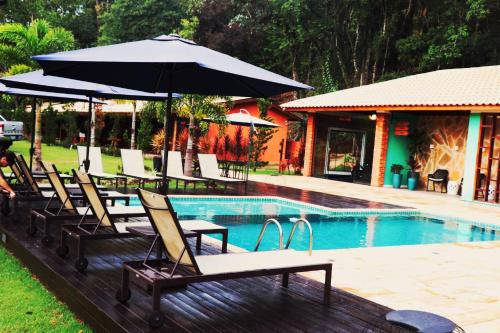 a group of chairs and an umbrella next to a pool at Pousada Santa Thereza in Serra Negra