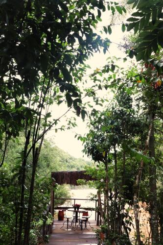a table and chairs on a wooden walkway with trees at Pousada Santa Thereza in Serra Negra