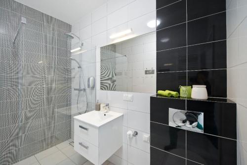 ein weißes Bad mit einem Waschbecken und einer Dusche in der Unterkunft Nova Motlava Old Town Apartment in Danzig