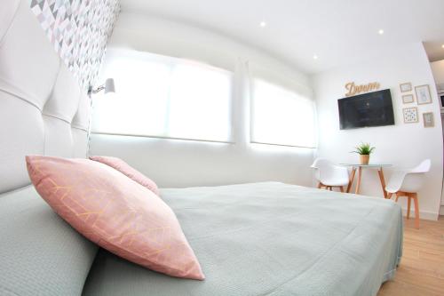 a white bedroom with a bed with a pink pillow at New Central Studio Torremolinos in Torremolinos