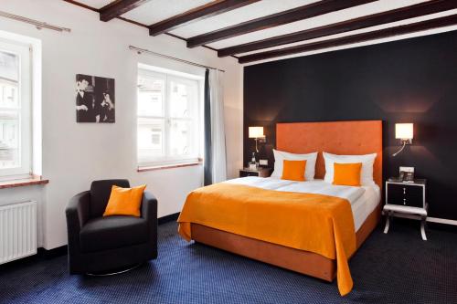 um quarto com uma cama grande e uma cadeira em Gildors Hotel Atmosphère em Dusseldorf