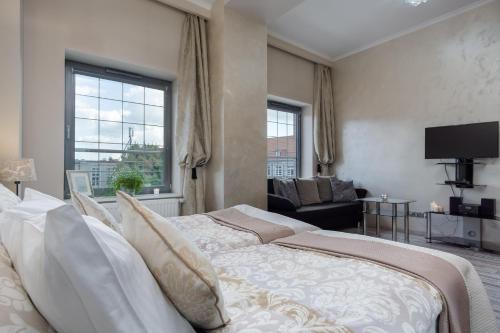 - une chambre avec un lit, un canapé et une télévision dans l'établissement Elite Apartments Tartaczna Deluxe, à Gdańsk