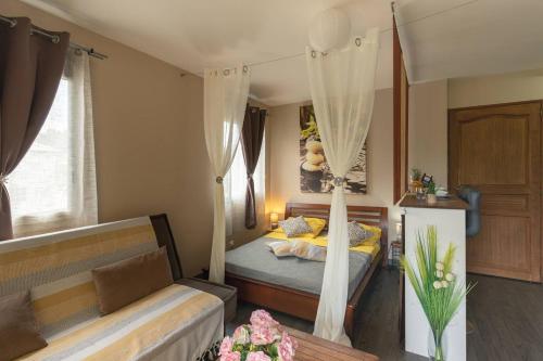 a bedroom with a bed and a couch at La Kazette - Votre Studio de Vacances à l Île de La Réunion in Saint-Louis
